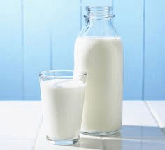 A pitcher of milk and a glass of milk on a table