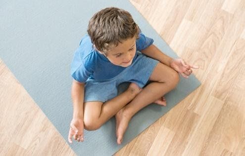 A kid meditating on a yoga mat
