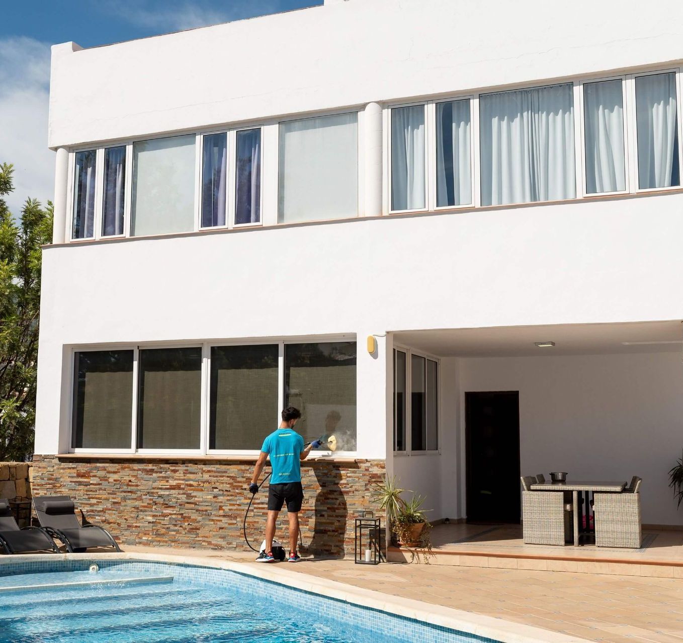 Un hombre con una camisa azul está de pie junto a una piscina.