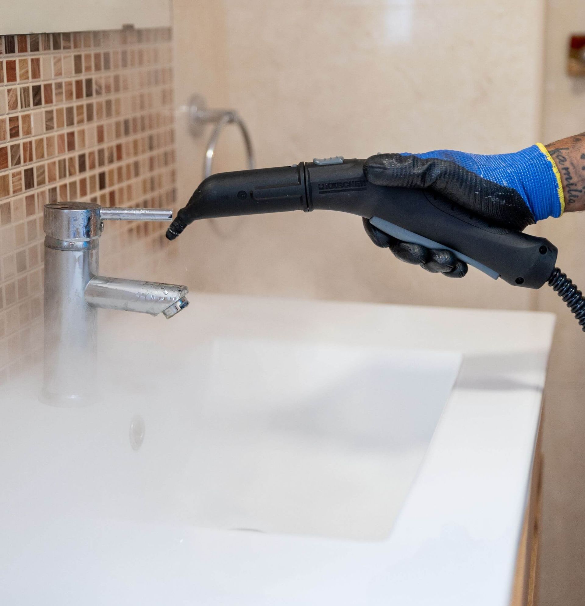 Una persona está limpiando un lavabo del baño con un limpiador a vapor.