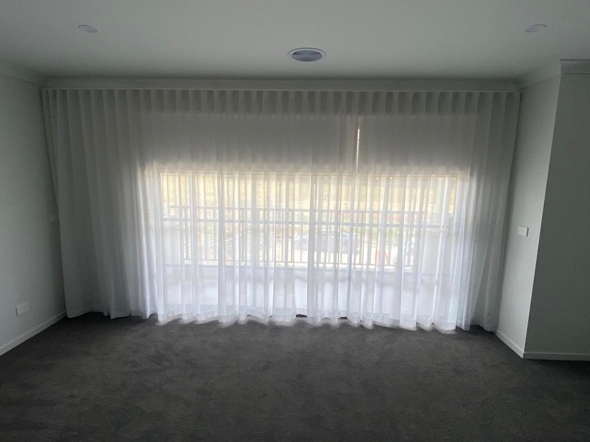 A Living Room With A Large Window And White Curtains — Night & Day Blinds and Awnings in Pakenham, VIC