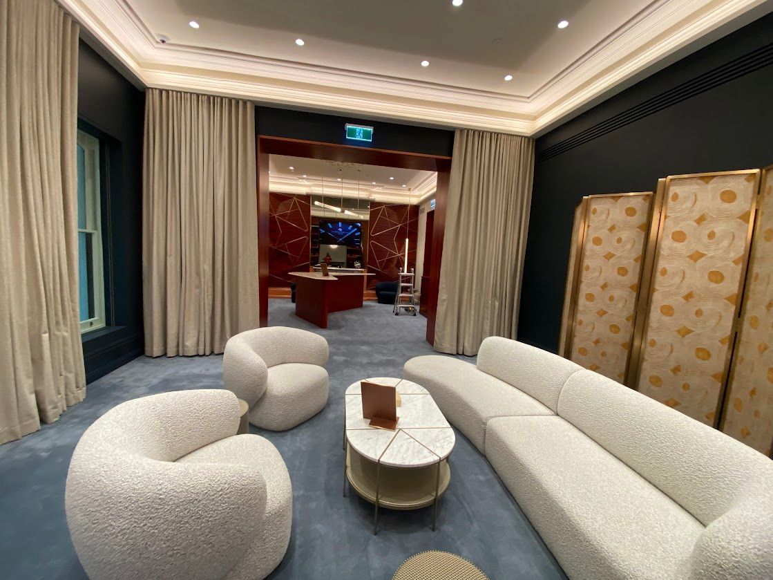 A Room With White Couches A Blue Carpet And White Curtains — Night & Day Blinds and Awnings in Pakenham, VIC