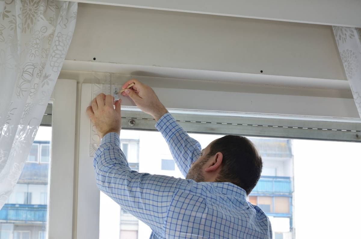 A window treatment installer at work helping with a shade installation near Baltimore.
