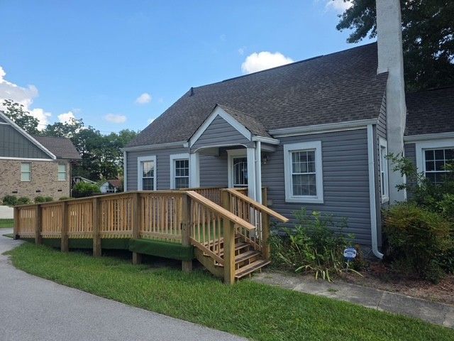 Gray house with a wooden accessibility ramp and stairs leading to the front door