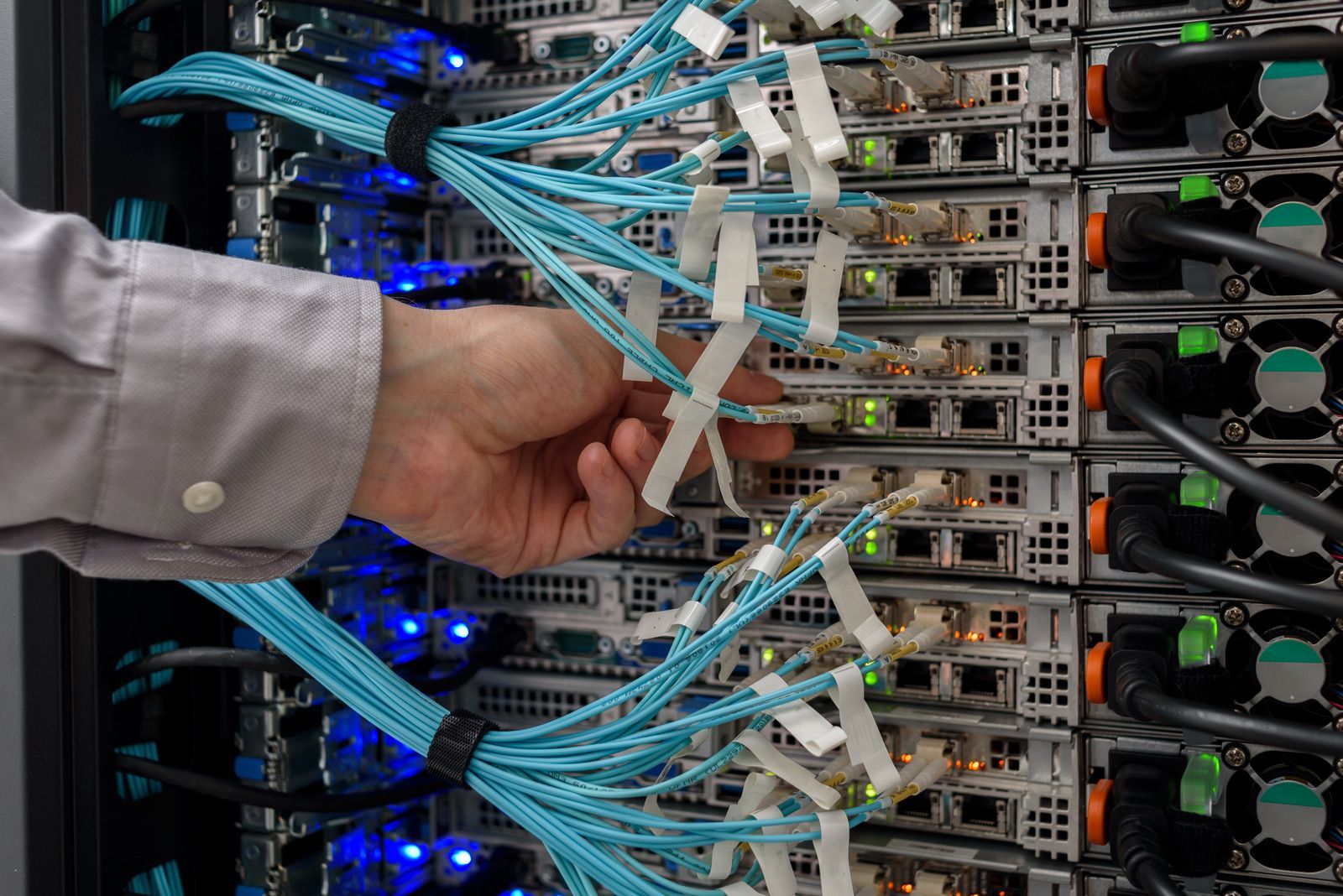 Three technicians review documents beside server racks in a data center.