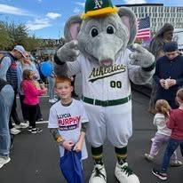 Oakland Athletics mascot posing with a child at an outdoor fan event