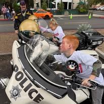 Police officers and children in a small police car during a community event