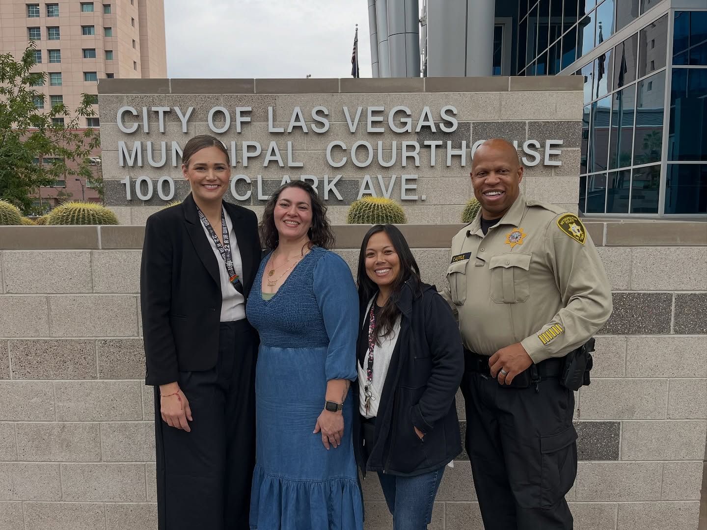 Four people posing on courthouse steps in front of a City of Las Vegas Municipal Court sign.