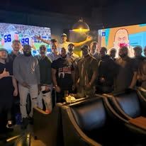 Crowded indoor event with a large trophy and illuminated screens in the background