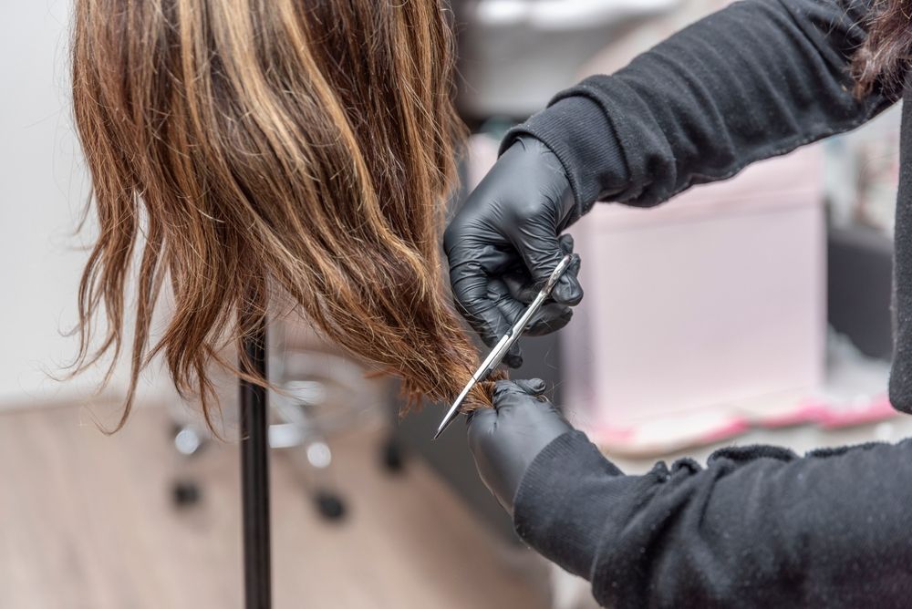 A woman is cutting a mannequin 's hair with scissors.