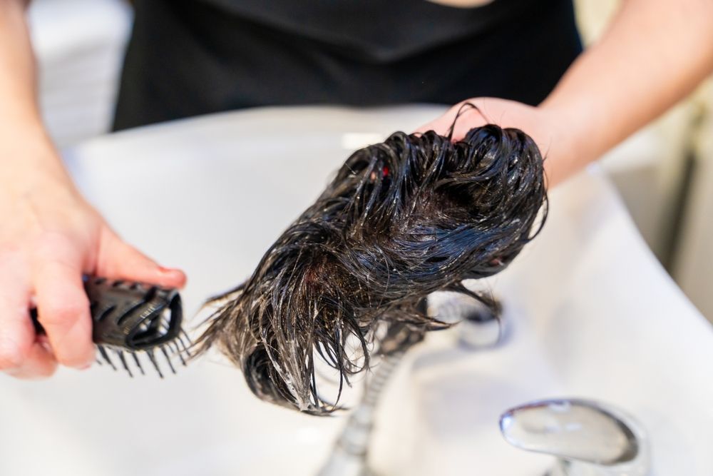 A person is brushing their hair in a sink.