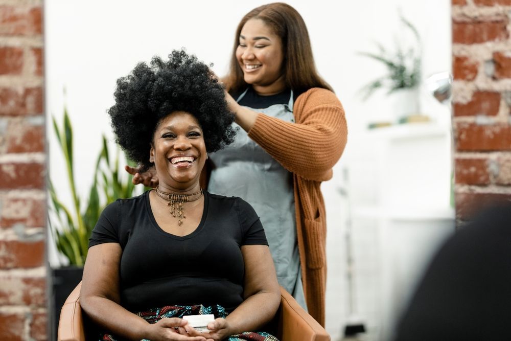 A woman is getting her hair done by a hairdresser in a salon.