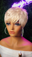 Close-up of a blonde mannequin head with short hair, makeup, and a white off-shoulder top against a dark background.
