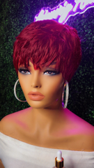 Close-up of a mannequin head with short magenta hair and silver hoop earrings against a dark glittery background