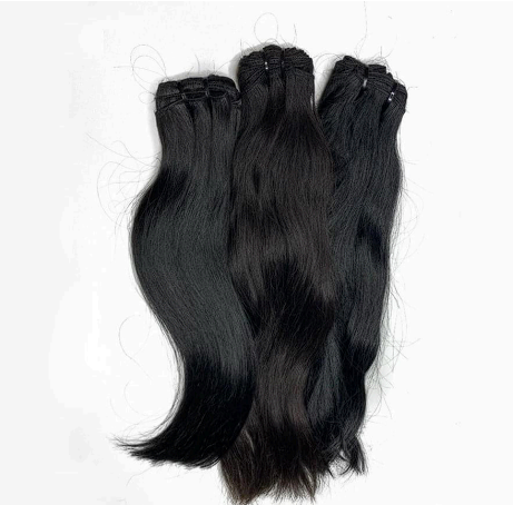 Three bundles of black hair are stacked on top of each other on a white surface.