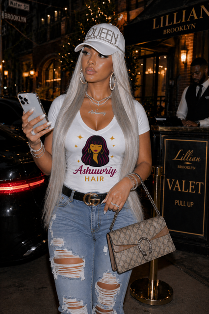 Woman in a silver top and ripped jeans holding a phone and handbag outside a restaurant at night