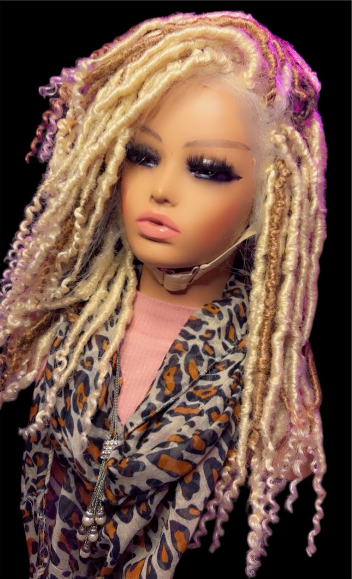 Mannequin head with blonde dreadlocks, dramatic makeup, wearing leopard print jacket.