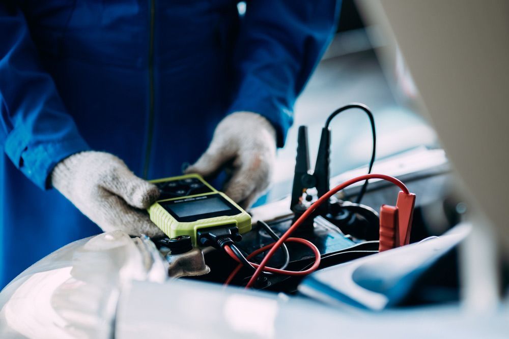 A Man Is Working On A Car Battery With A Multimeter — Edmonton Car Air in Port Douglas, QLD