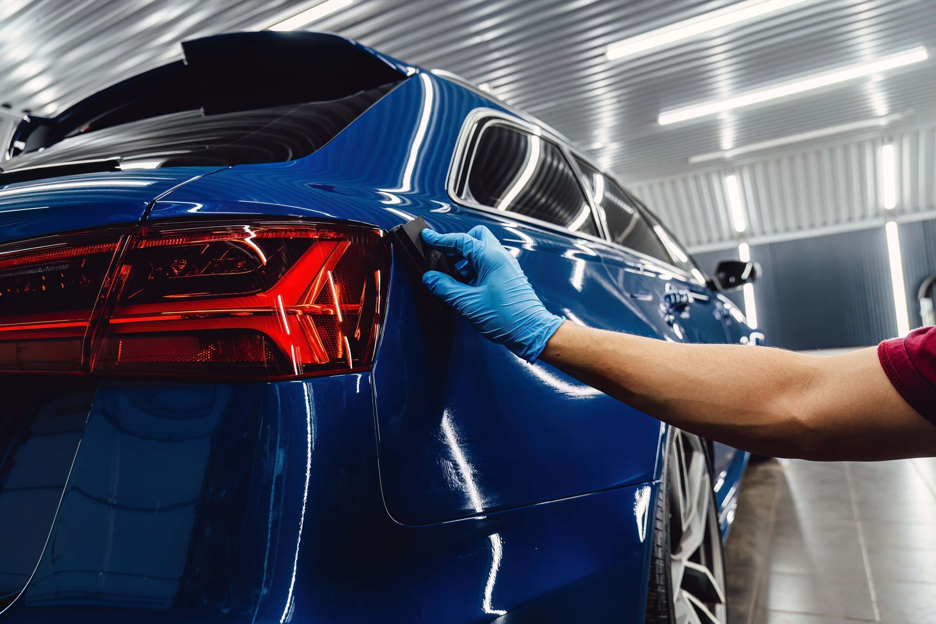 Blue car being wiped clean in a bright auto detailing bay
