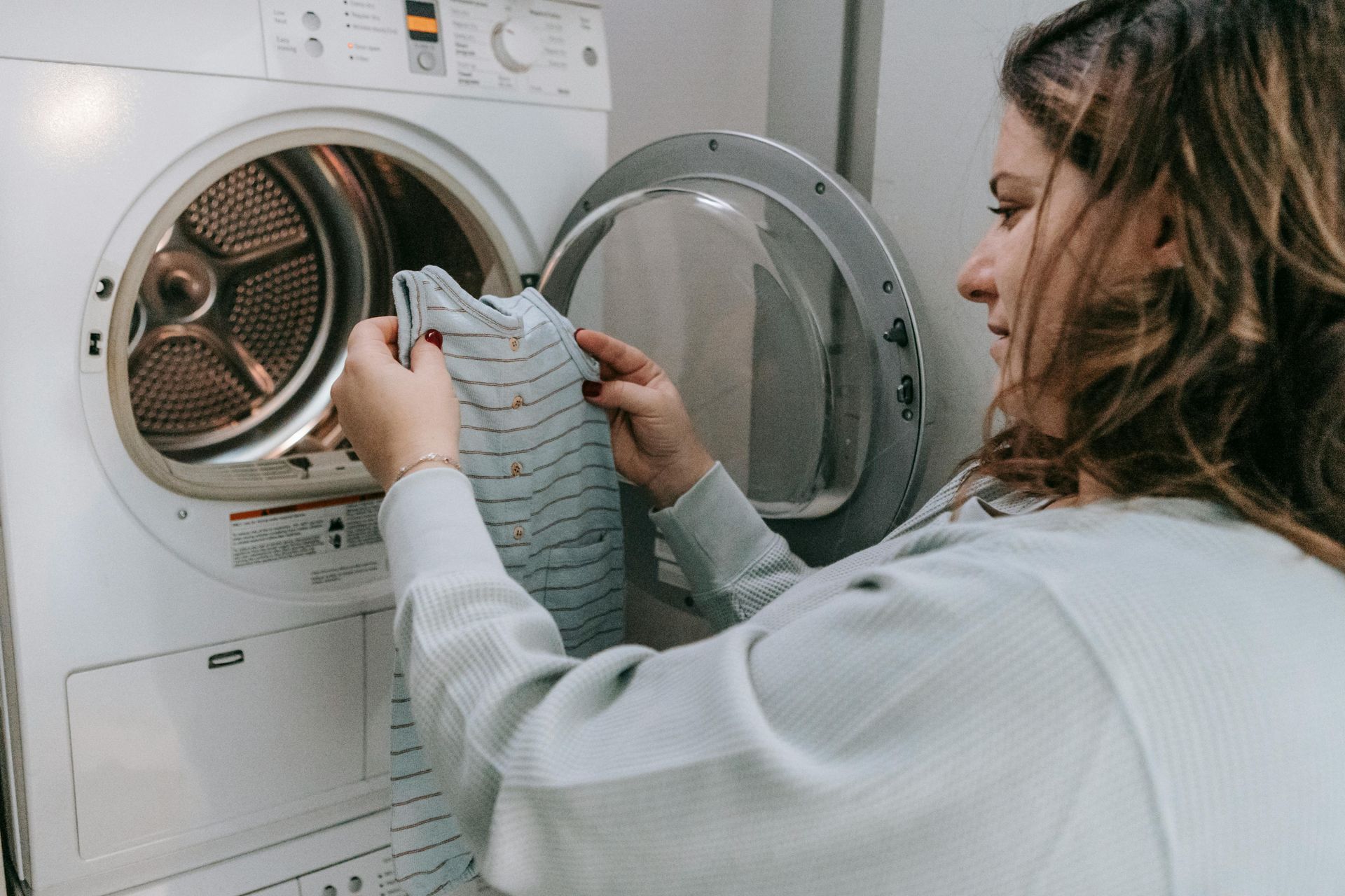 Person loading clothes into a front-loading washing machine in a laundry room