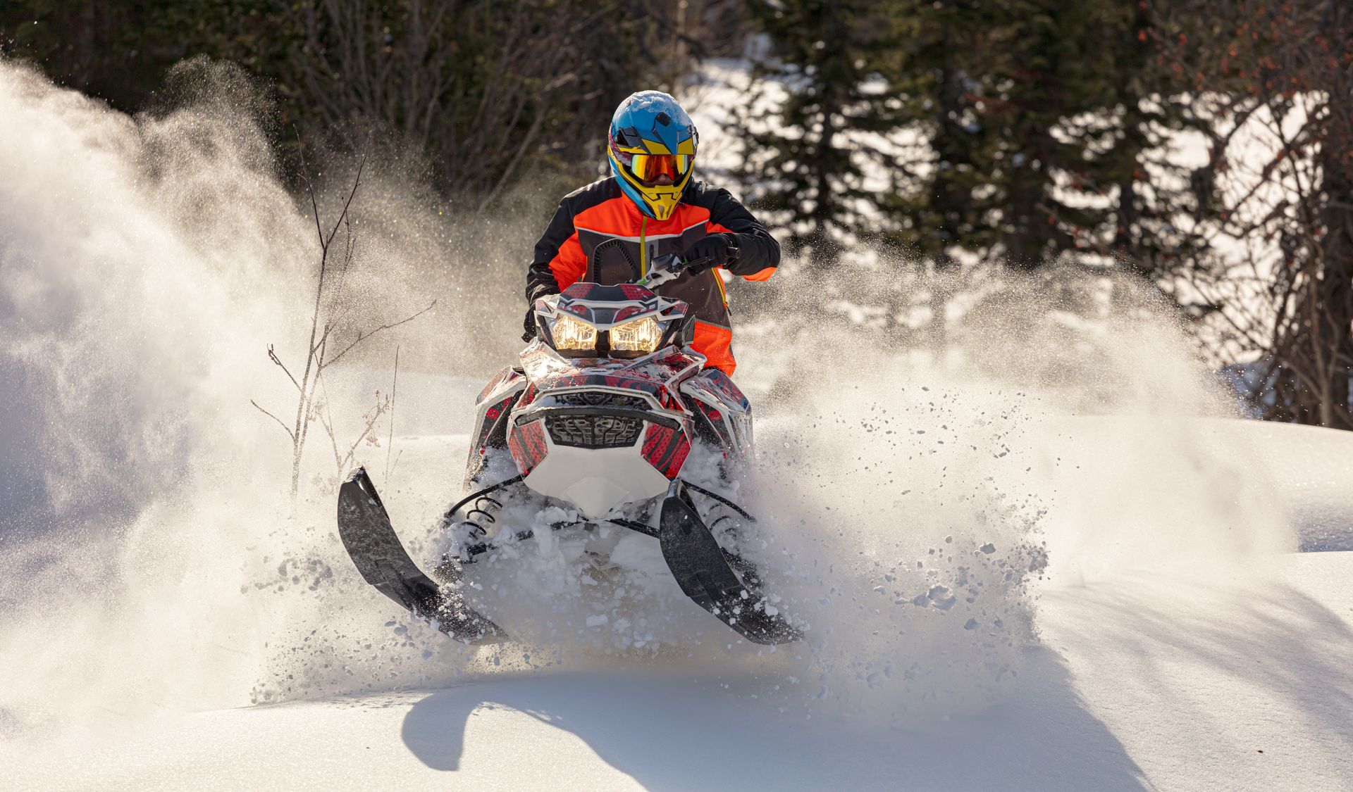 A man is riding a snowmobile through the snow.