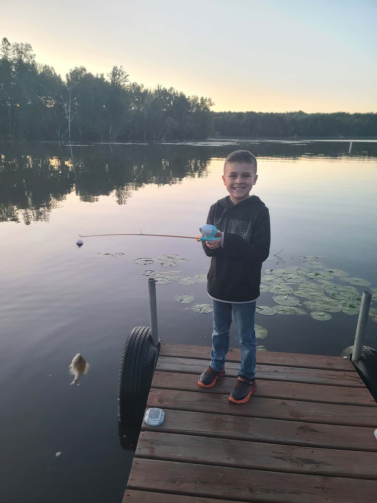 A young boy is holding a large fish in front of a boat.