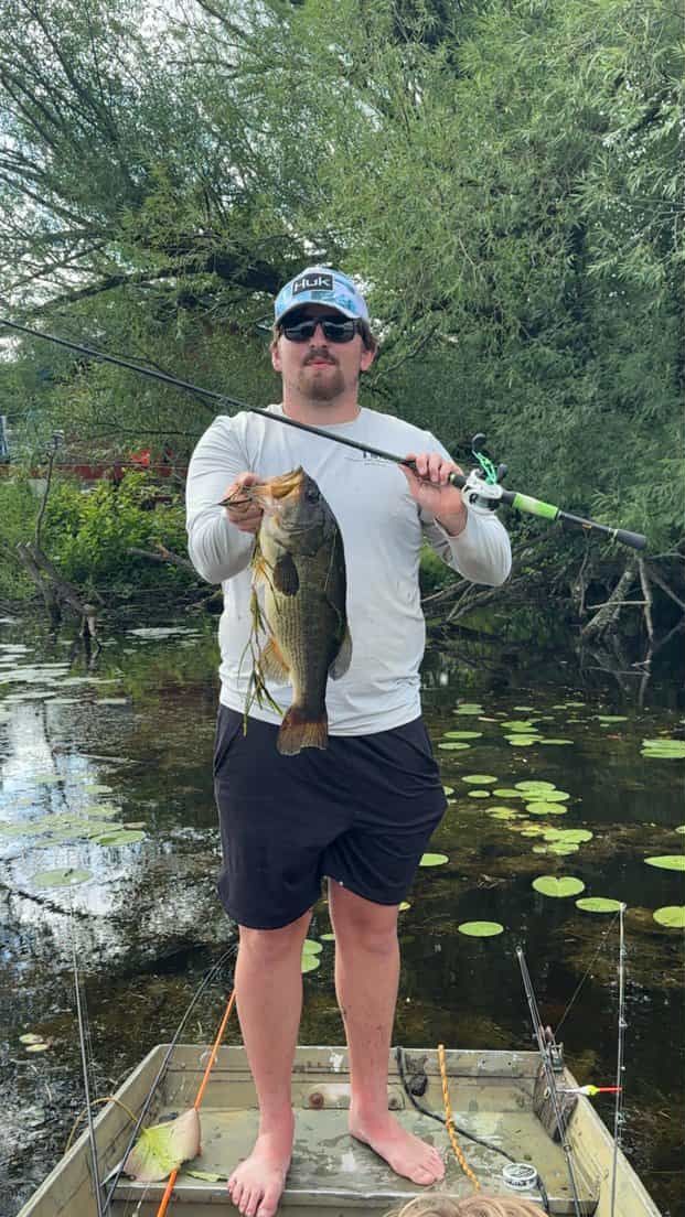 A man is standing on a boat holding a large fish