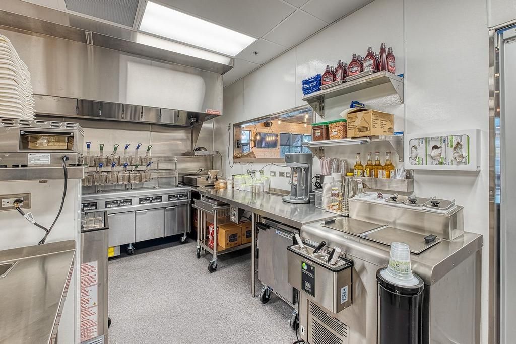 A kitchen with a lot of stainless steel appliances and a trash can.