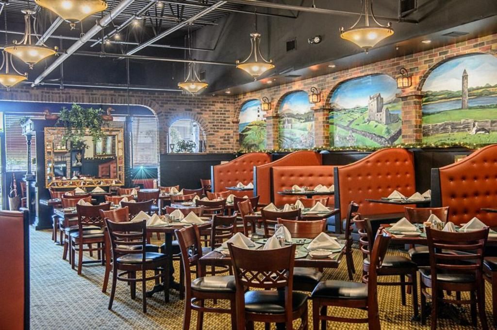 A restaurant filled with tables and chairs and paintings on the walls.