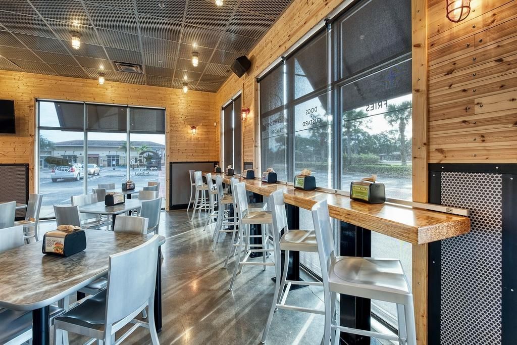 A restaurant with tables and chairs and a lot of windows.