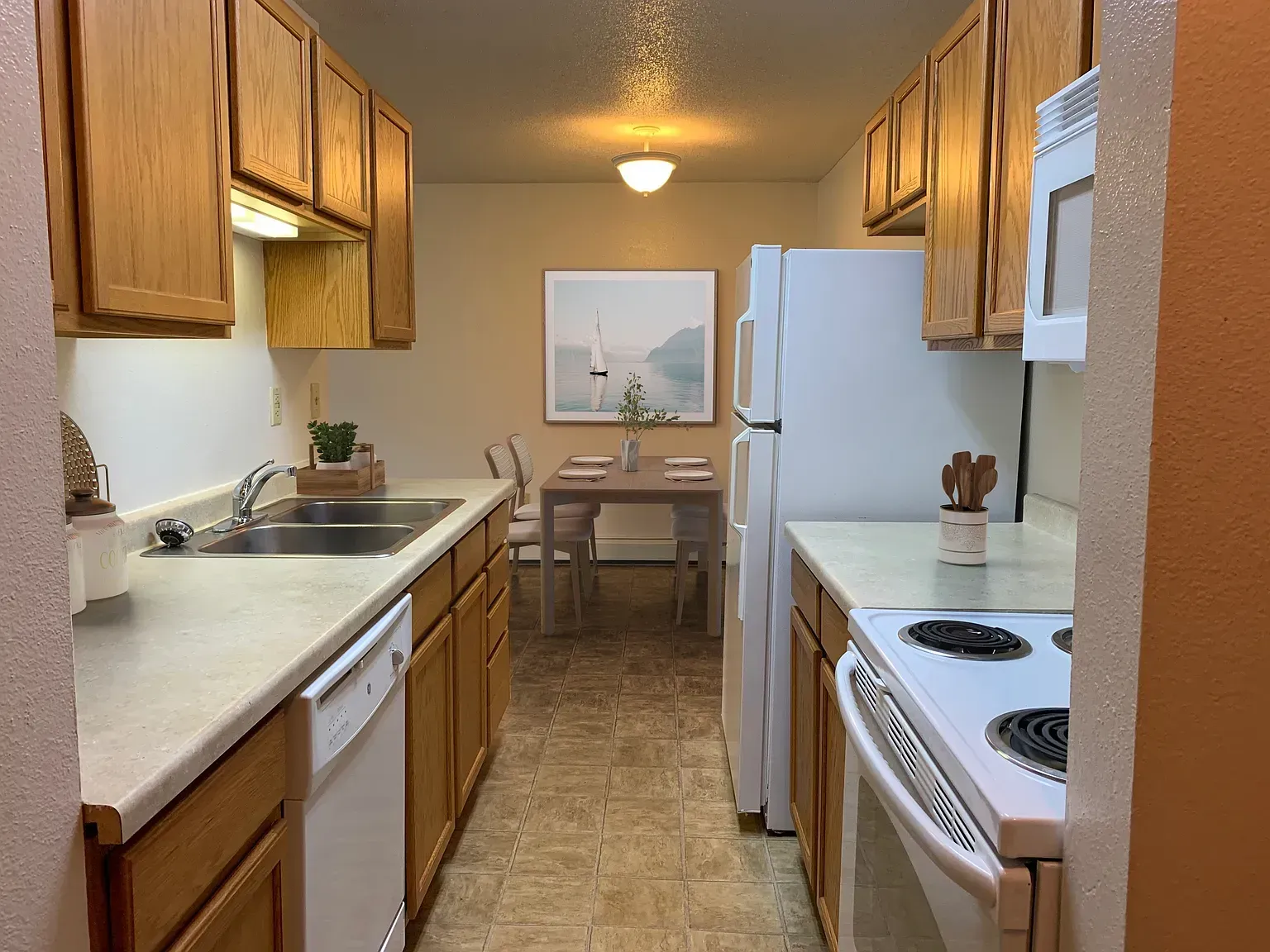 Kitchen with light wood cabinets, white appliances, and a dining table in the background.