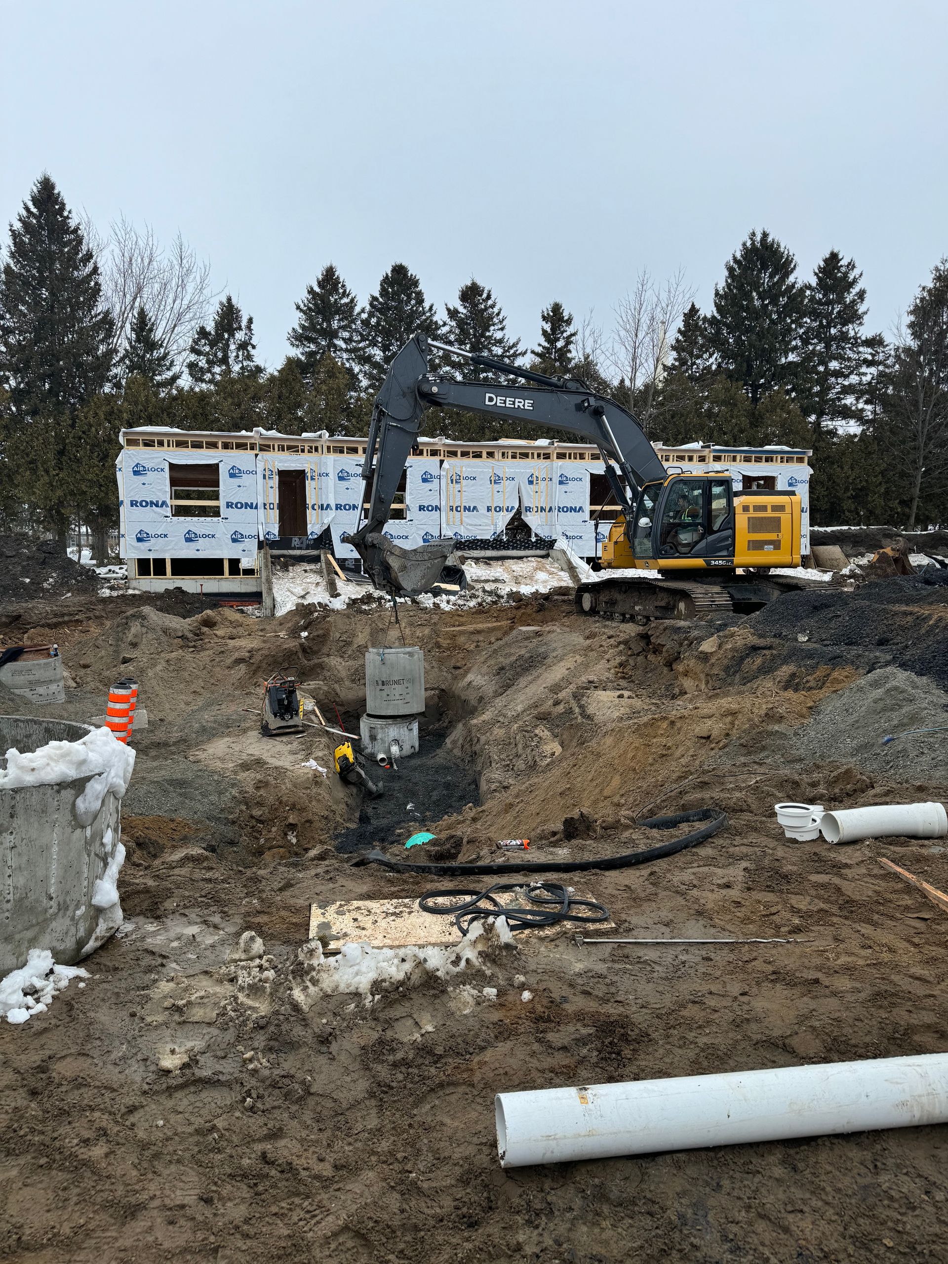 Une grande excavatrice creuse un trou devant une maison en construction.