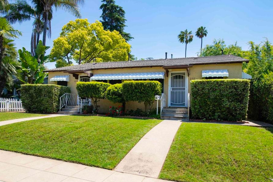 A house with a lush green lawn and a white picket fence