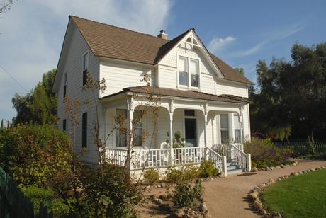 A white house with a brown roof and a large porch
