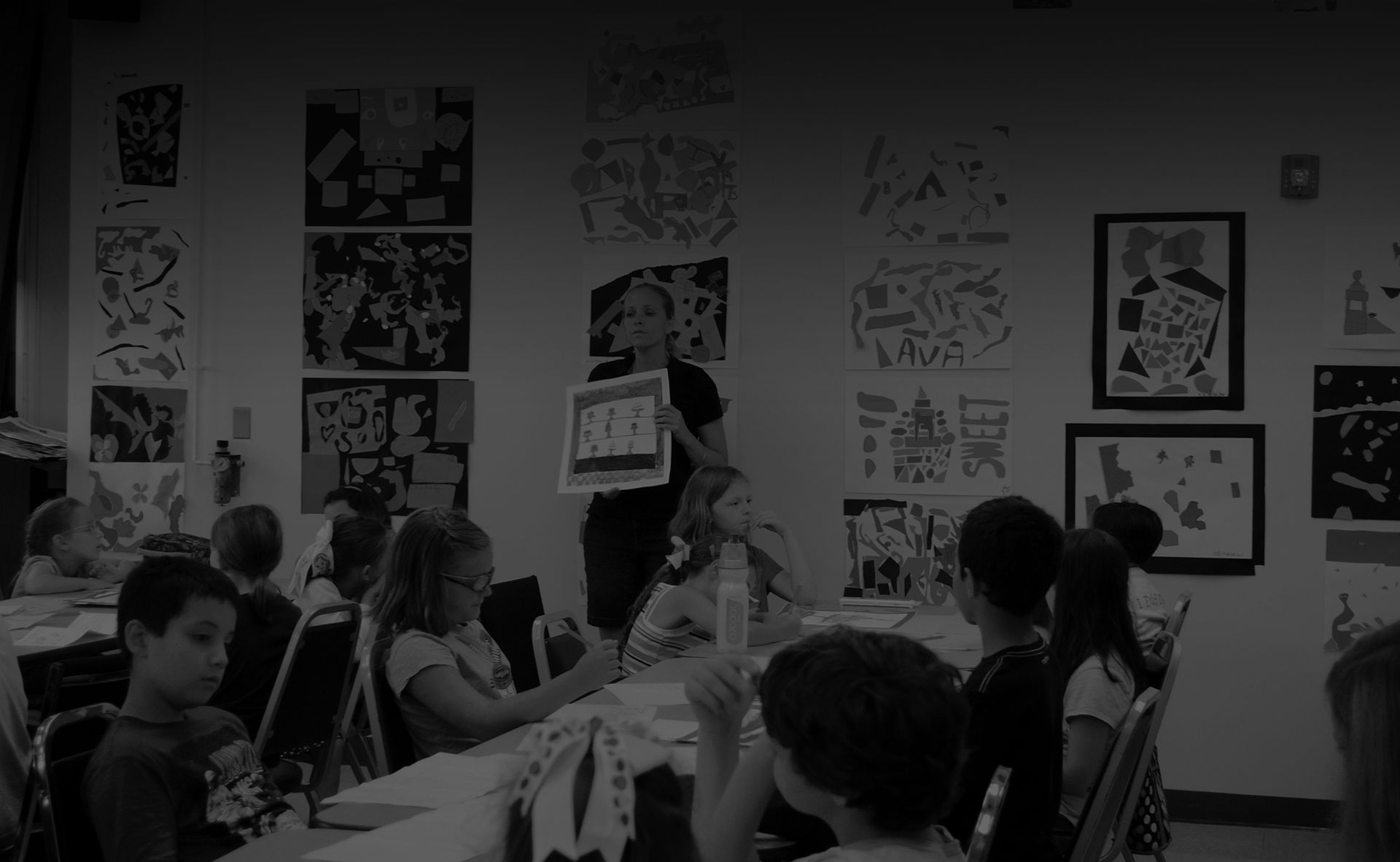 A group of children are sitting at a table in a classroom.