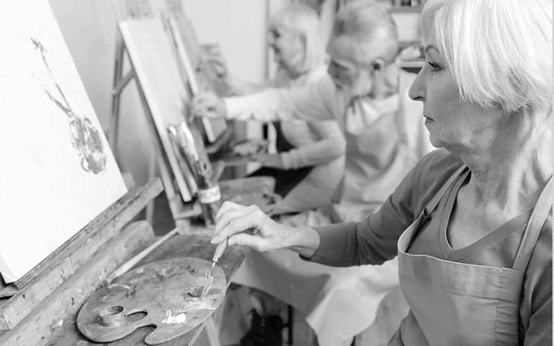 A woman is painting a picture on an easel in a black and white photo.