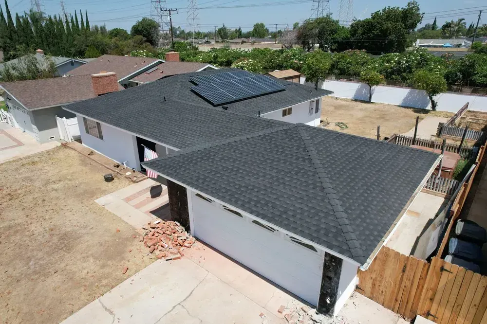 Aerial view of a single-story house with a new dark gray shingled roof and installed solar panels.