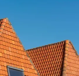 Steep, orange clay-tiled roofs under a clear blue sky.