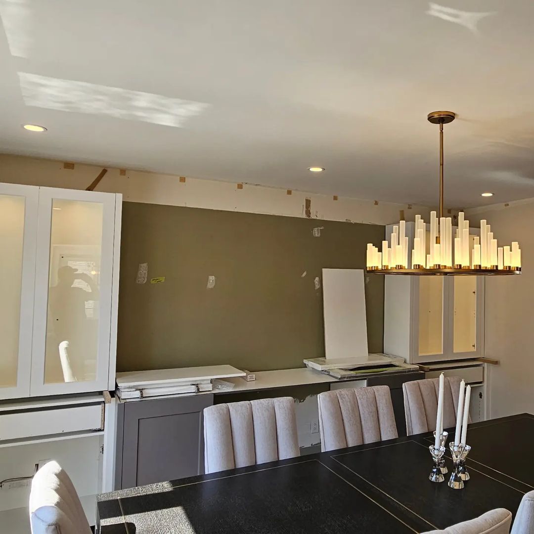 A dining room with a table and chairs and a chandelier hanging from the ceiling