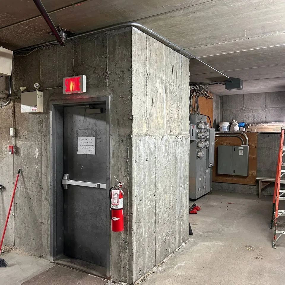 Une pièce avec une porte et un extincteur sur le mur.