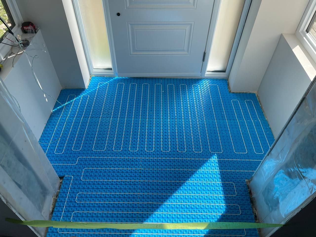 Un couloir avec un sol bleu et une porte blanche.