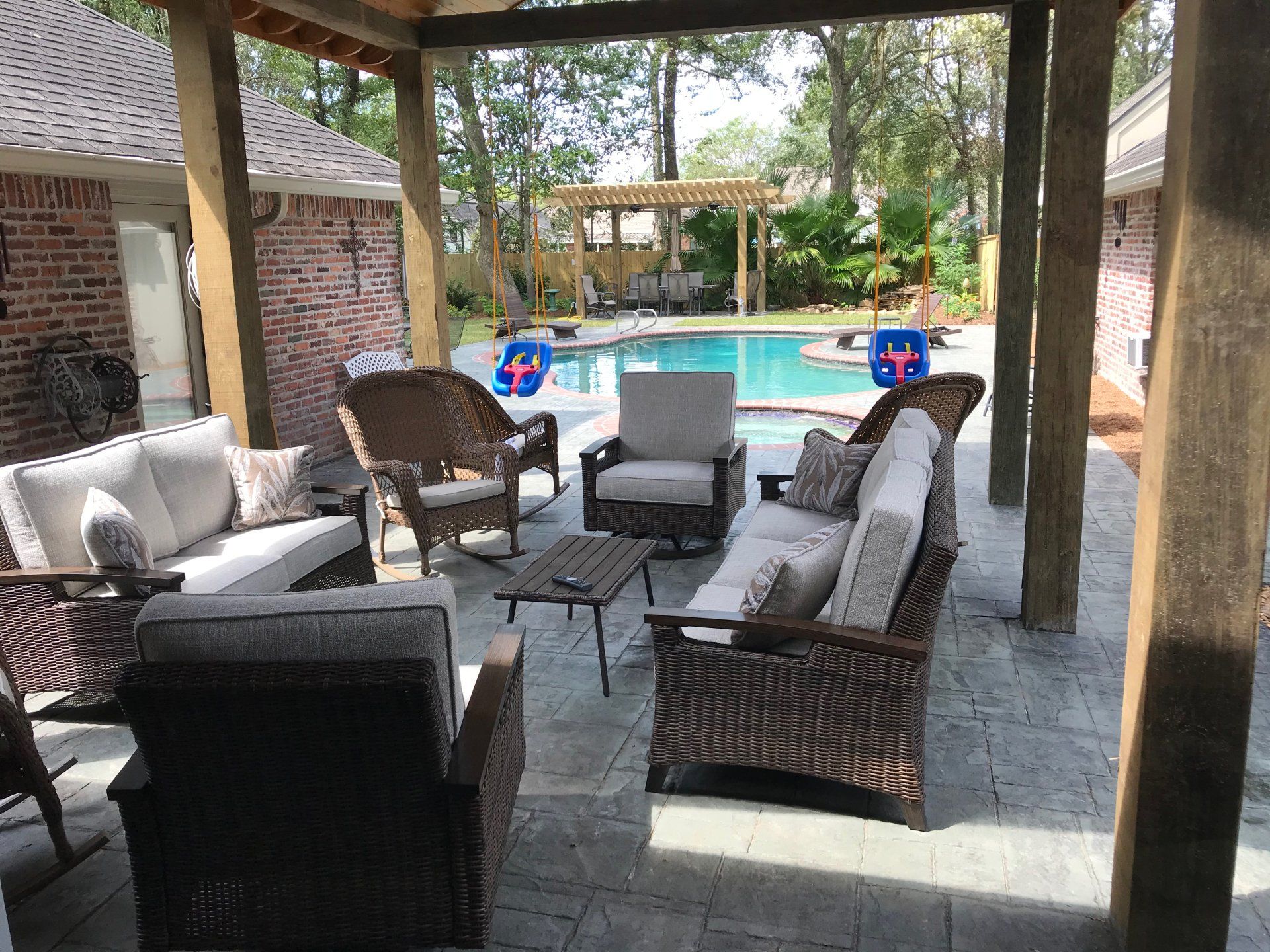 Patio with outdoor furniture overlooking a swimming pool.