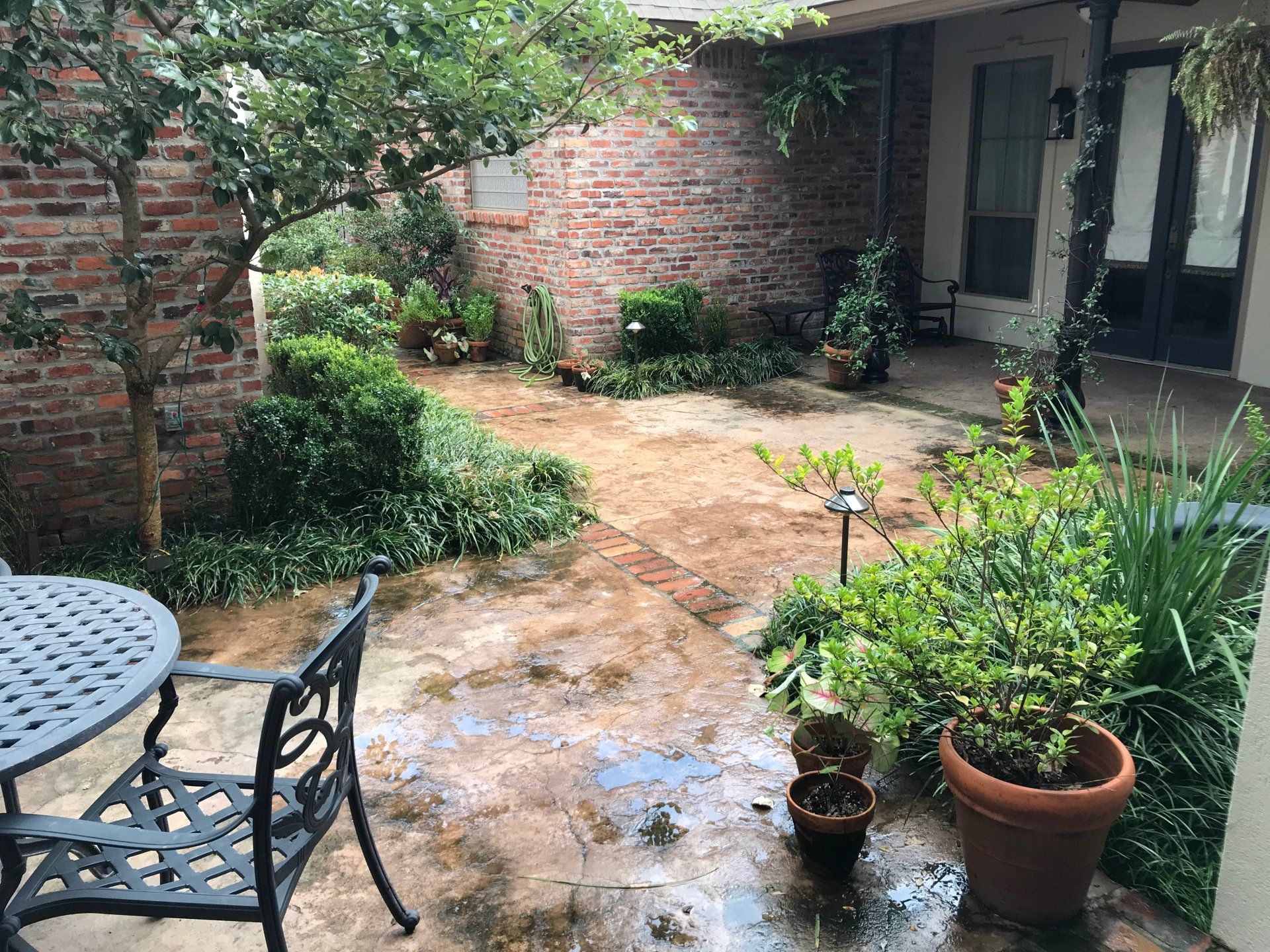 Courtyard with brick walls, patio furniture, and various plants.