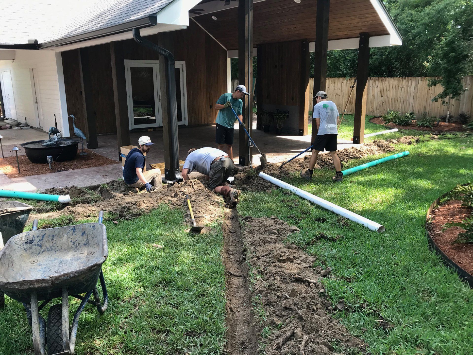 Construction workers installing drainage pipes in a yard.
