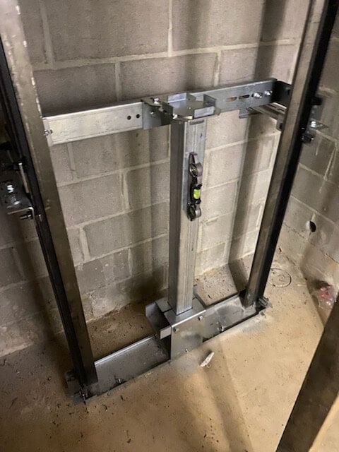 Metal frame installed on a concrete block wall, likely for an elevator or lift.