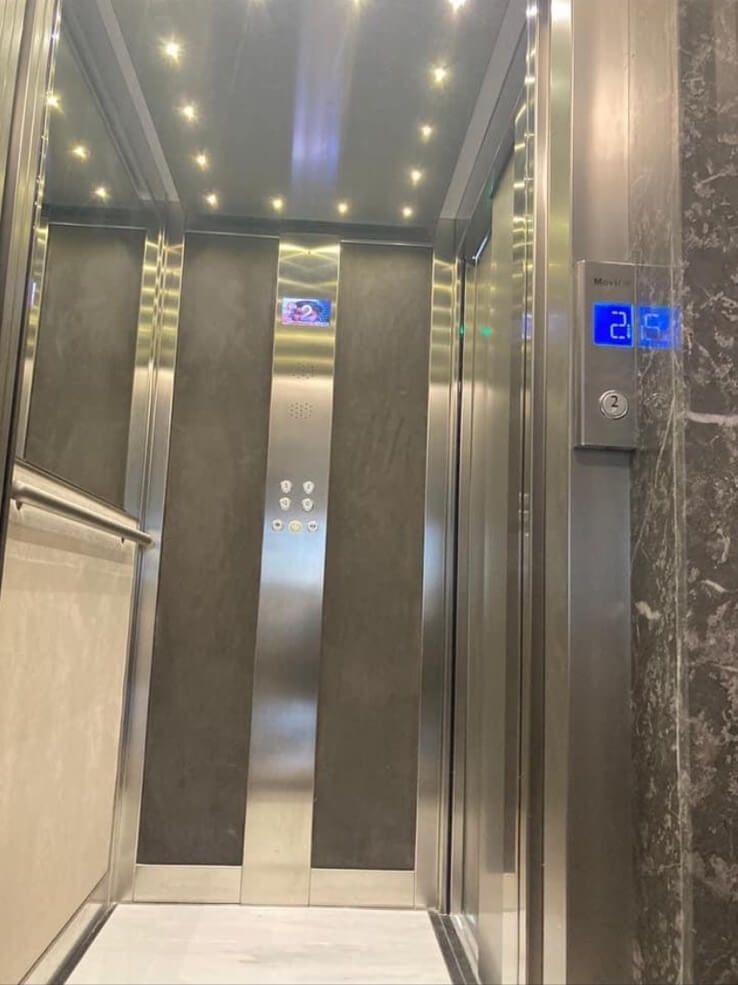 Elevator interior, stainless steel and grey with the number 2 illuminated on the control panel.