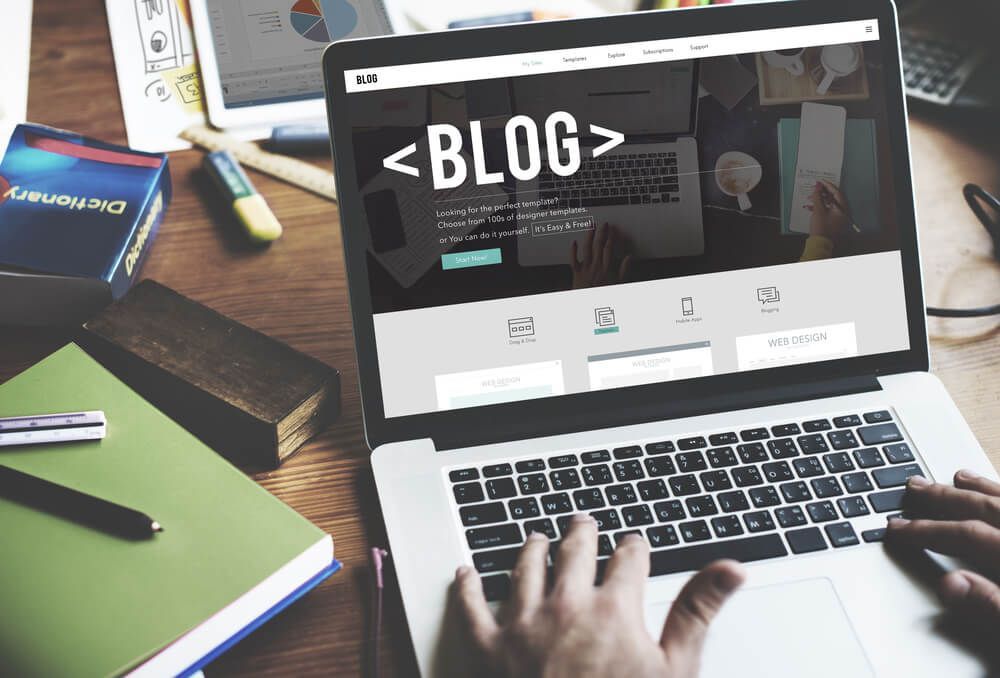 A person is typing on a laptop with the word blog on the screen.