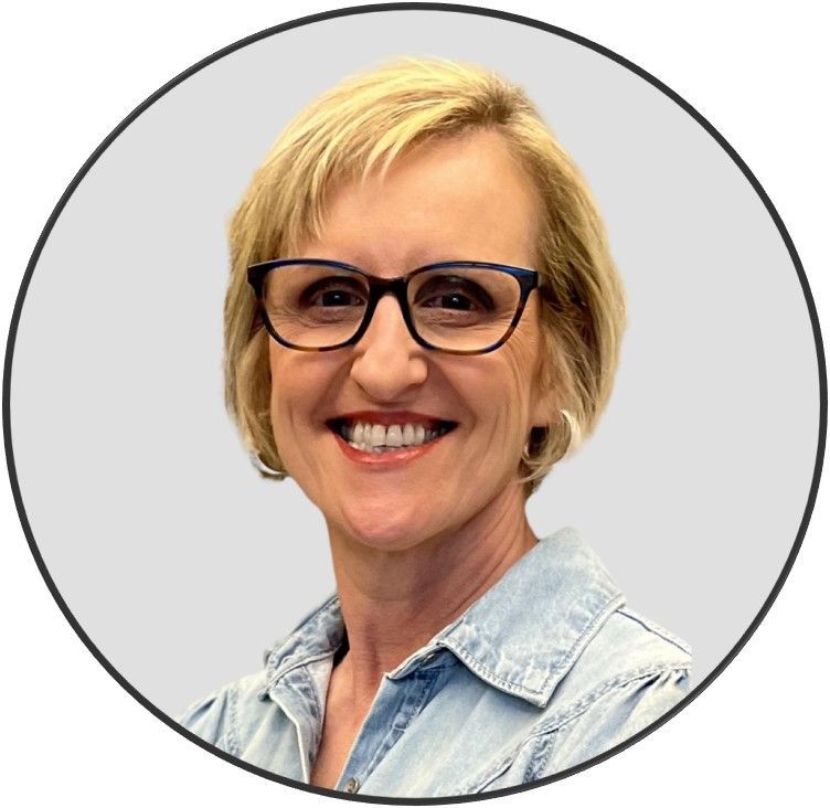 A woman wearing glasses and a blue shirt is smiling