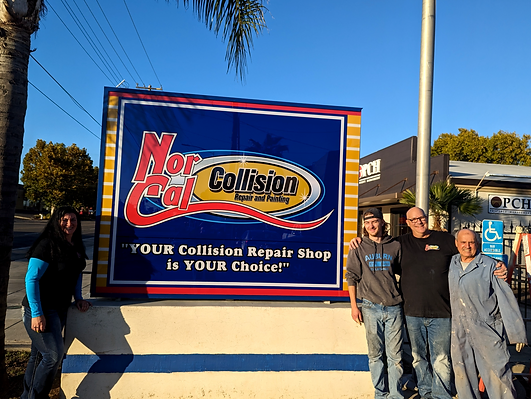A group of men standing in front of a collision repair shop sign