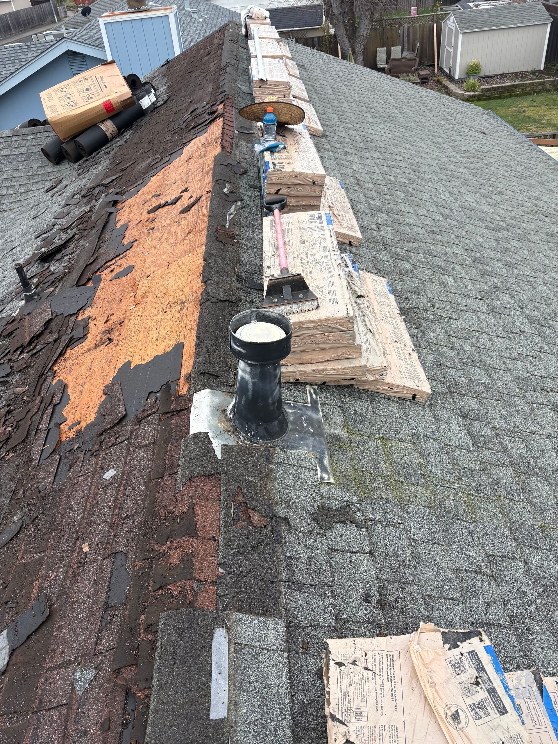 Roof with old shingles partially removed, new shingles being installed.